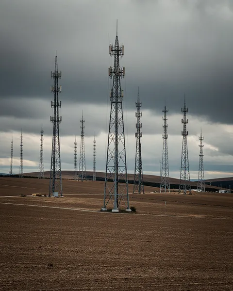 Multiple telecomm towers on rural ridge under overcast sky